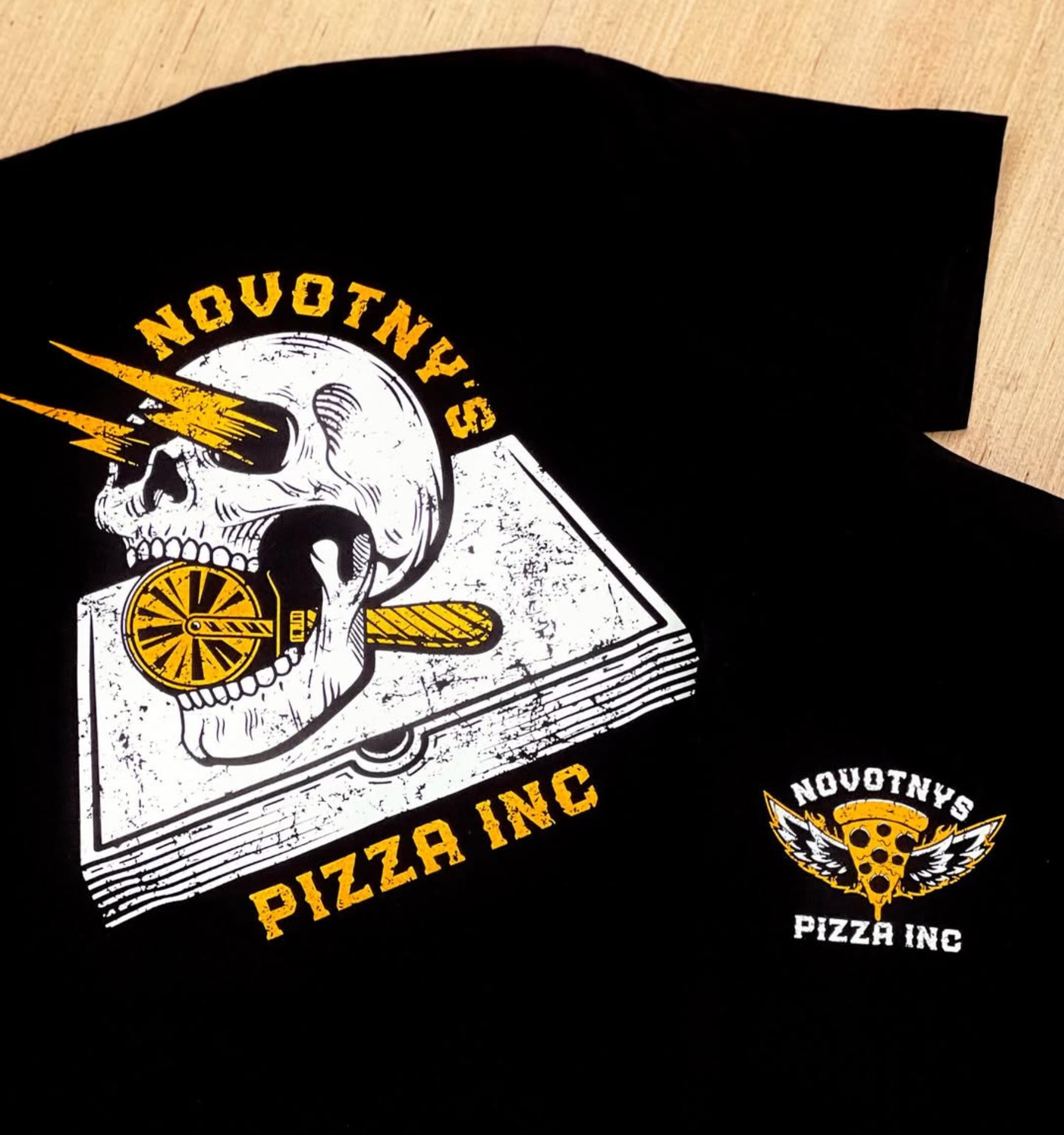 Novotny’s Pizza skull graphic printed in yellow and white on black shirts